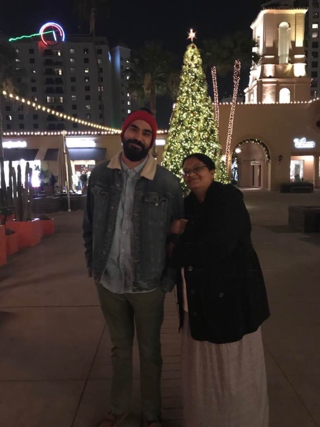 My mom and me in front of a lit Christmas tree at night